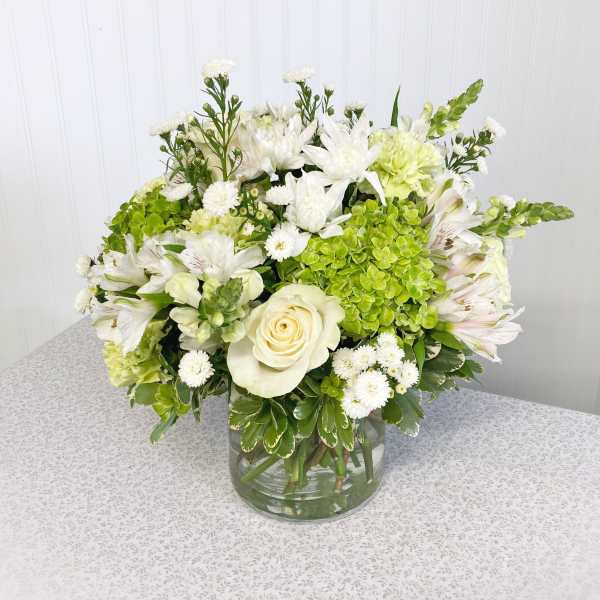 White and green floral arrangement in a clear glass vase