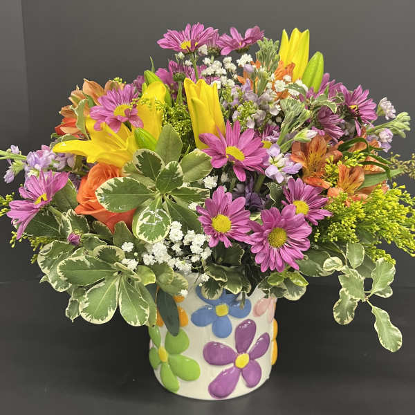 Mixed bouquet of daisies, lilies, and roses in a floral ceramic vase
