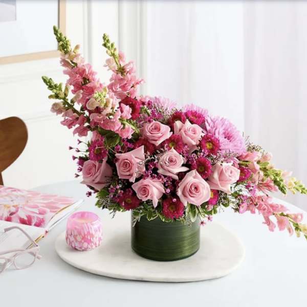 Pink roses and mixed pink flowers in a green vase on a table