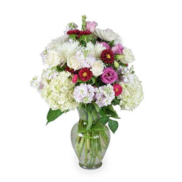Mixed bouquet of white, pink, and red flowers in a clear glass vase