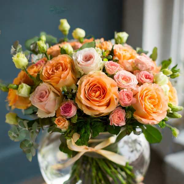 Bouquet of peach and pink roses in a clear glass vase