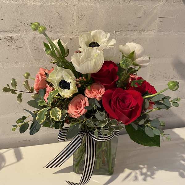 Bouquet of red and blush roses with white anemones in a glass vase