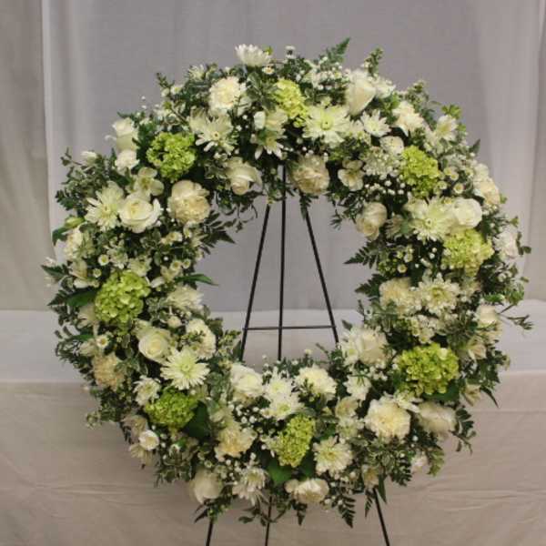 Large white and green floral wreath on a stand