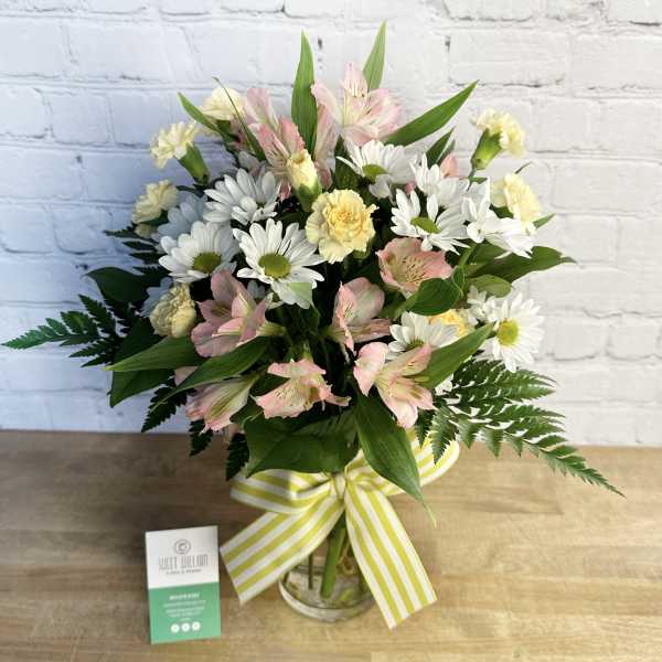 Bouquet of pink alstroemeria, white daisies, and yellow carnations in a glass vase