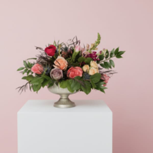 Mixed pink and peach rose arrangement in a silver pedestal bowl
