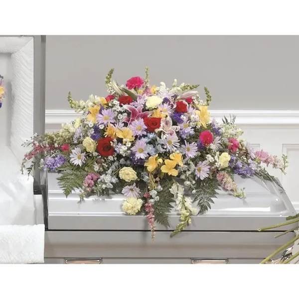 Large mixed flower spray on a white casket
