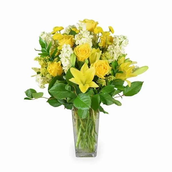 Yellow roses and lilies in a clear glass vase