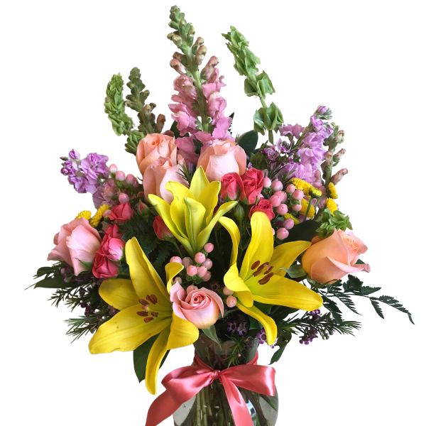 Mixed bouquet of yellow lilies, pink roses, and purple flowers in a glass vase