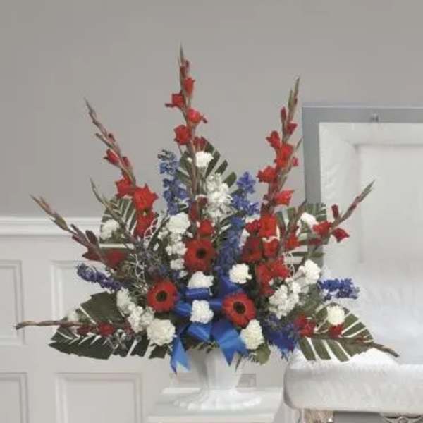 Tall red, white, and blue floral arrangement in a white pedestal vase