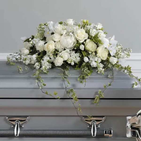 White floral arrangement on a gray casket with trailing ivy
