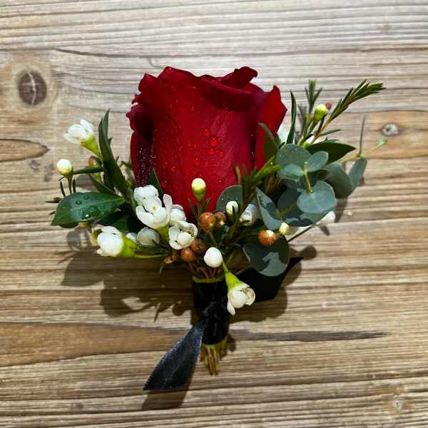 Red rose boutonniere with white waxflowers and eucalyptus