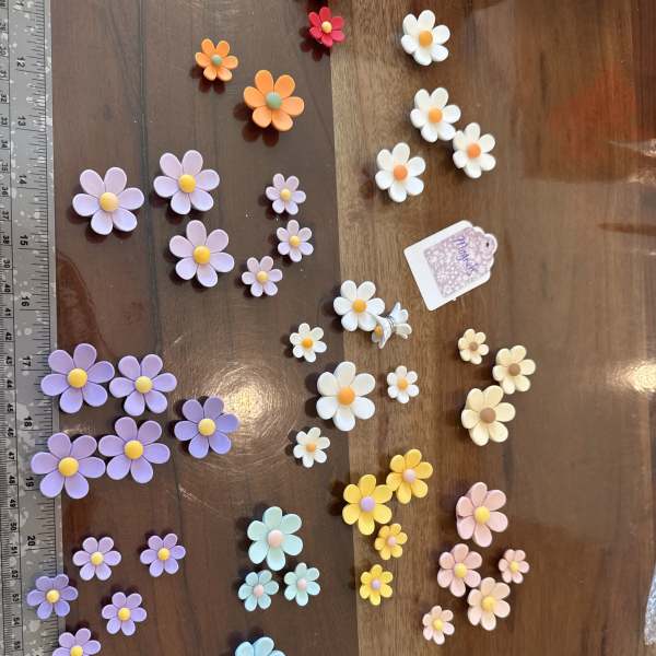 Assorted small pastel daisy decorations arranged on a wooden surface
