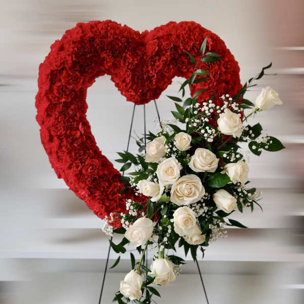 Red heart-shaped floral display with white roses on a stand