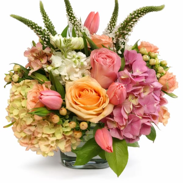 Mixed bouquet of roses, hydrangeas, and tulips in a glass vase