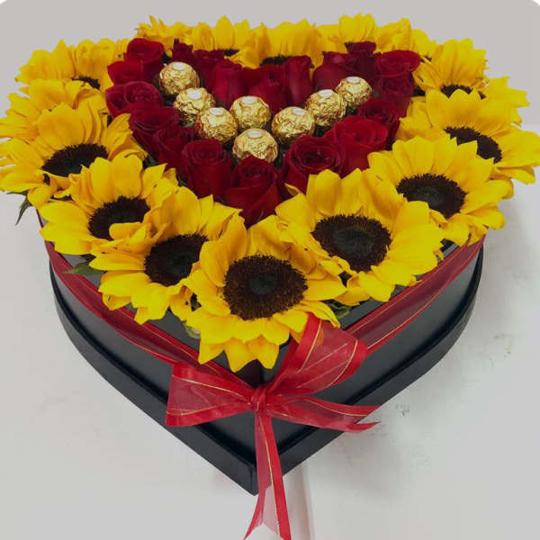 Heart-shaped box of red roses and yellow sunflowers with chocolates