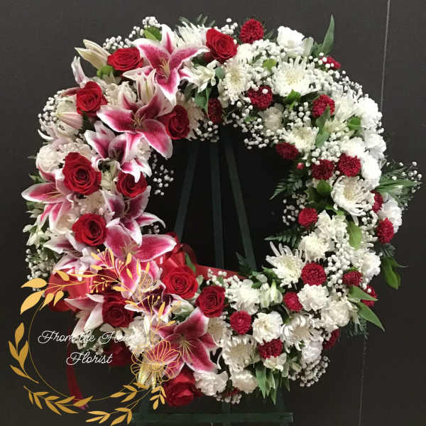 Heart-shaped floral wreath with red roses, pink lilies, and white flowers