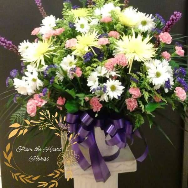 Large mixed flower arrangement with purple ribbon on a pedestal