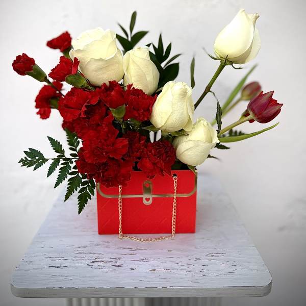 Red carnations and white roses in a red gift box