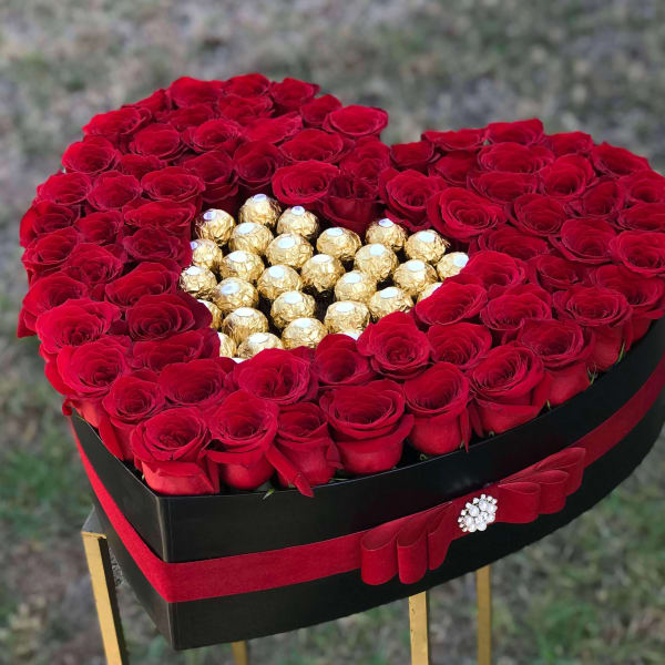 Heart-shaped box of red roses with gold-wrapped chocolates in the center