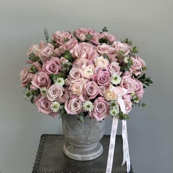 Pink rose bouquet in a gray urn vase with ribbon tails