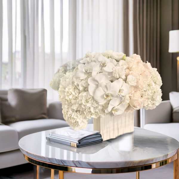 White floral arrangement in a rectangular vase on a round table
