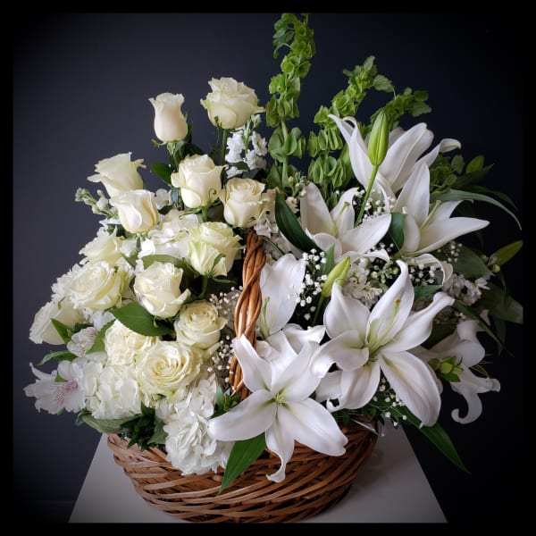 White roses and lilies arranged in a wicker basket