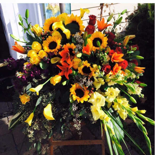 Large mixed floral spray with sunflowers, roses, lilies, and calla lilies