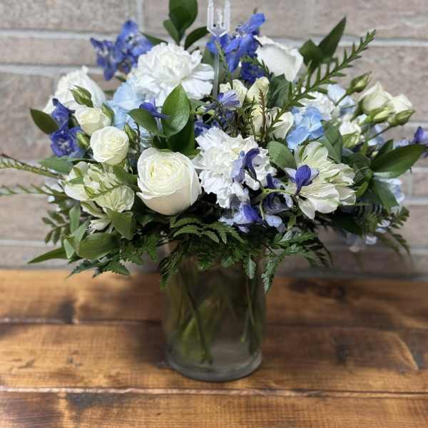 White and blue mixed flower arrangement in a clear glass vase.