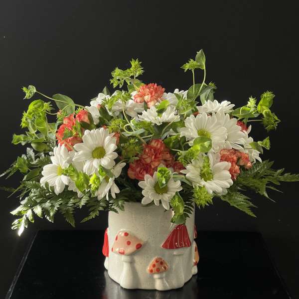 White daisies and pink carnations in a mushroom-decorated ceramic pot