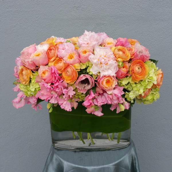 Pink and peach flowers arranged in a low glass vase