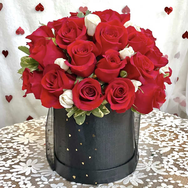 Red and white roses arranged in a black hatbox