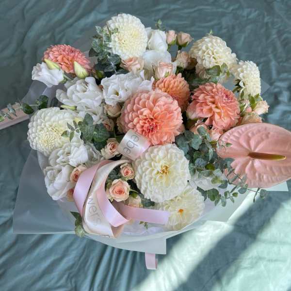 Bouquet of white and peach flowers with pink ribbon