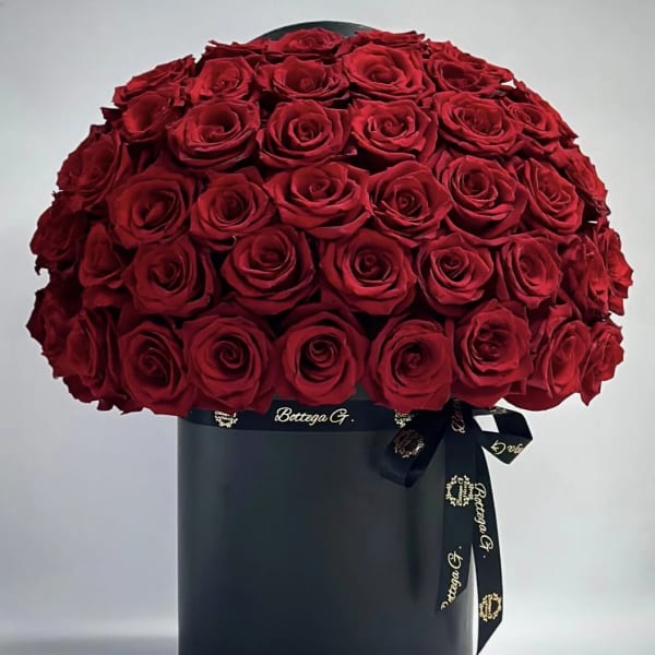 Large bouquet of red roses in a black hat box with ribbon