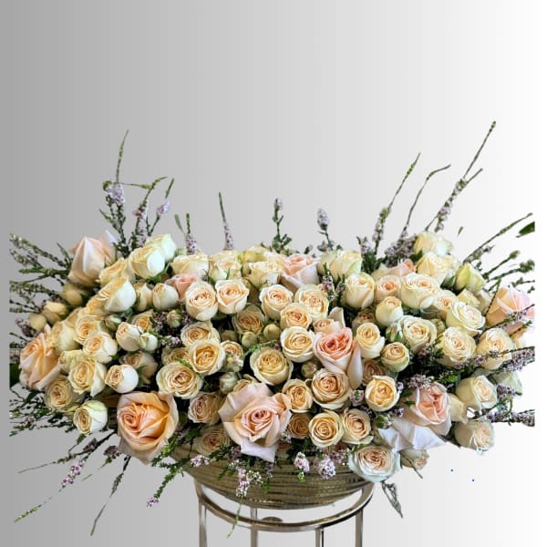 Large peach and cream rose arrangement in a low bowl vase