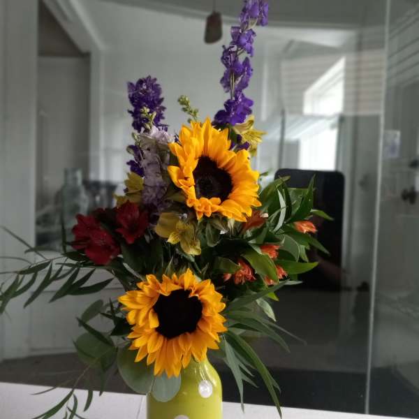 Sunflowers and mixed flowers in a yellow polka-dot vase