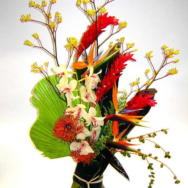Tropical flower arrangement in a glass vase with red and orange blooms