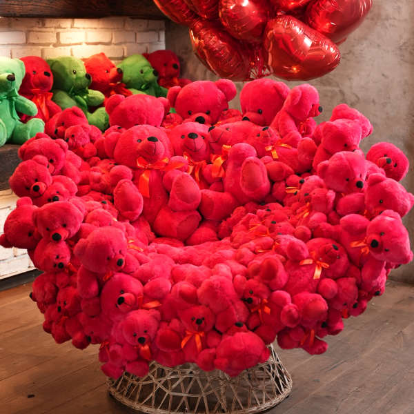Large heart-shaped display of red teddy bears with red balloons above