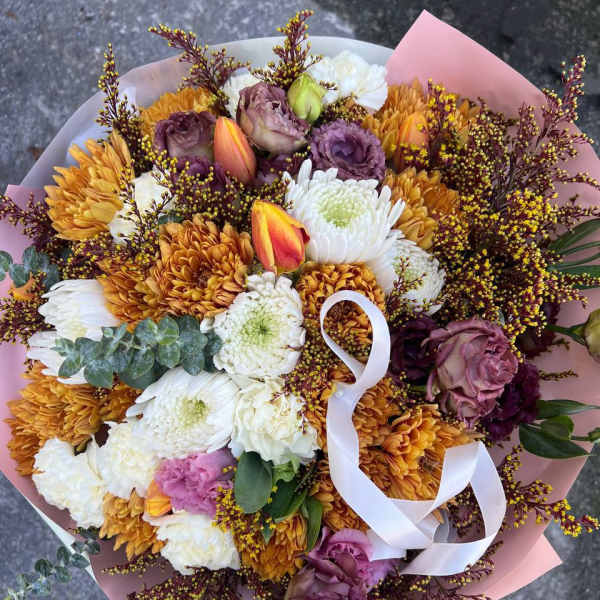 Bouquet of white, purple, and orange flowers wrapped in pink paper