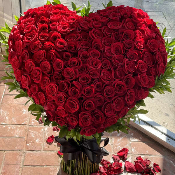 Heart-shaped bouquet of red roses tied with a black ribbon