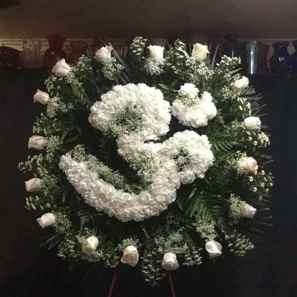 Large white funeral wreath with roses and clustered blooms