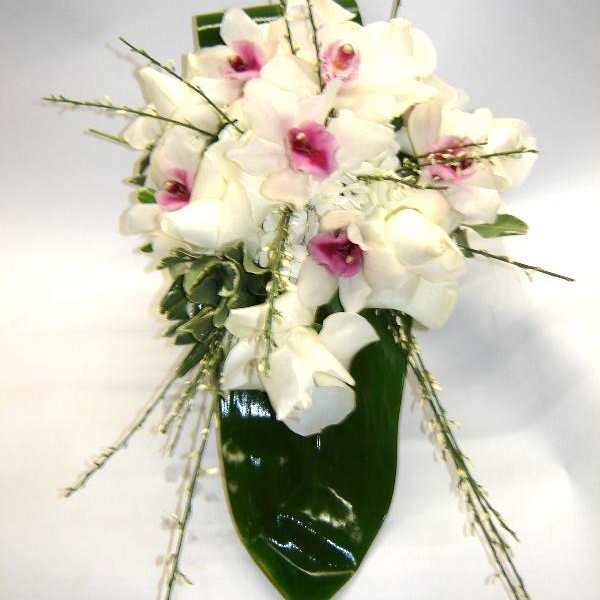 White orchids with pink centers arranged in a glossy green vase