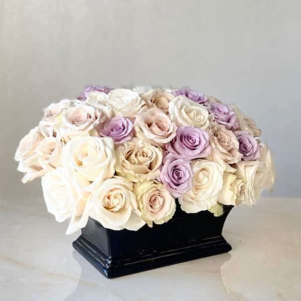 Cream and lavender roses arranged in a black vase