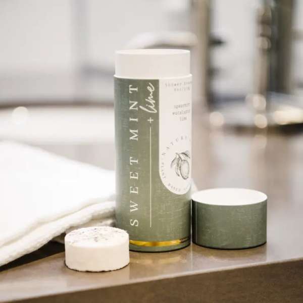 Mint + Lime scented candle in a green cylindrical container with a lid