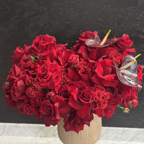 Red rose arrangement in a beige pedestal vase