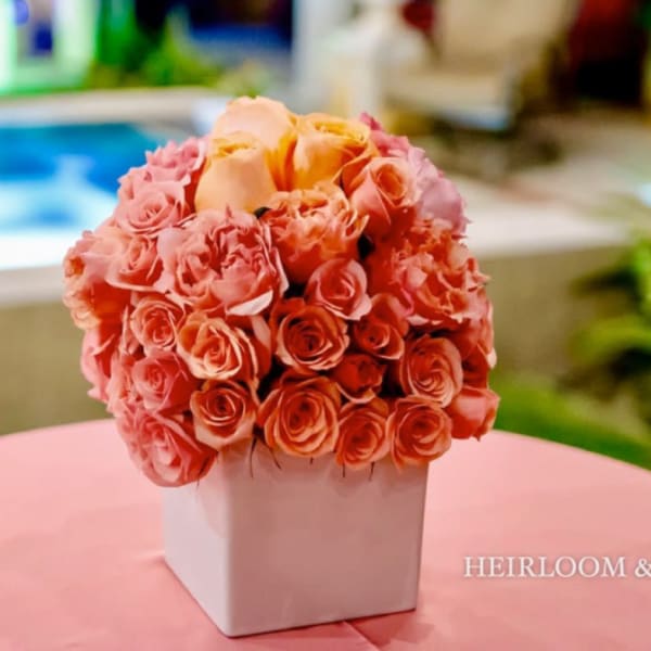 Peach and pink rose bouquet in a white square vase