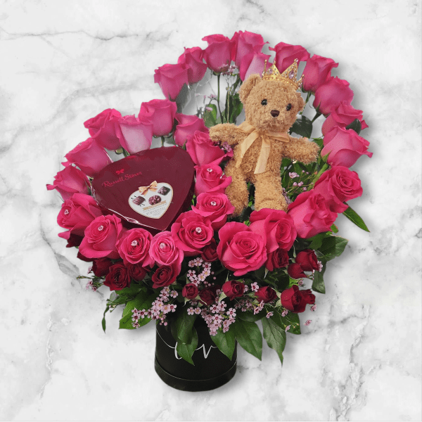 Pink rose arrangement with a teddy bear and heart-shaped chocolate box