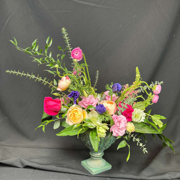 Mixed bouquet of pink, yellow, purple, and white flowers in a decorative urn vase