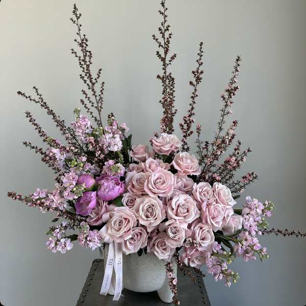 Pink roses and lilac flowers arranged in a gray vase