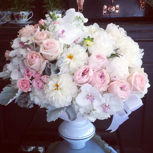 Pink and white floral arrangement in a white pedestal vase