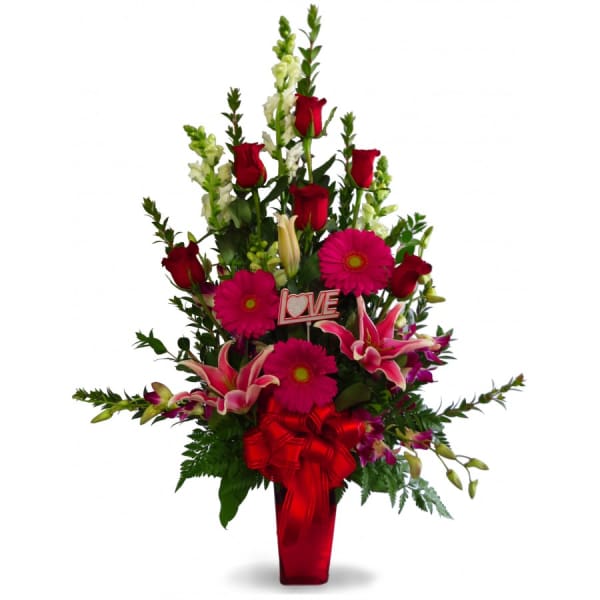 Tall bouquet of red roses, pink lilies, and gerbera daisies in a red vase